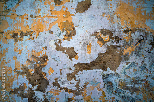 An aged and cracked cement wall with yellow green blue mood and tone