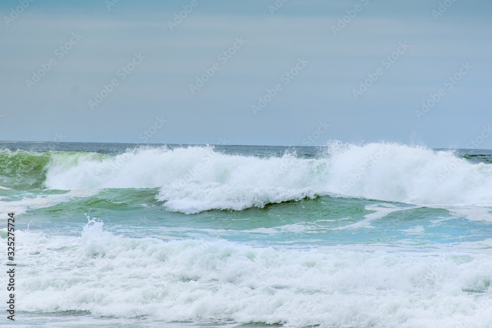 Ocean waves with white foam splashes on a dull cloudy day