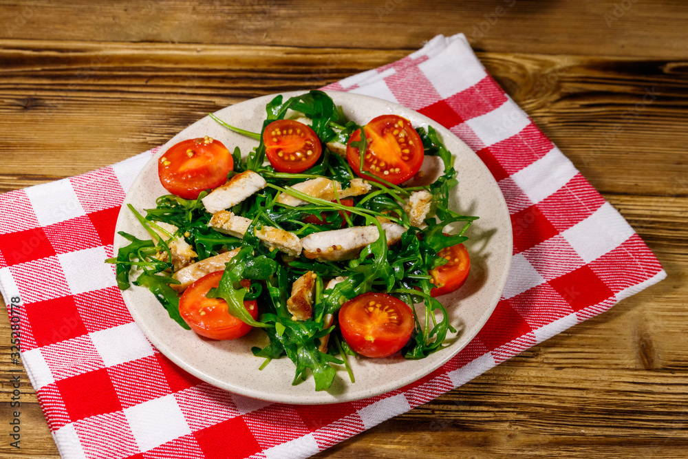 Tasty salad of fried chicken breast, fresh arugula and cherry tomatoes on wooden table Tasty salad of fried chicken breast, fresh arugula and cherry tomatoes on wooden table