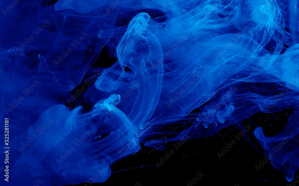 Fototapeta premium Blue watercolor ink in water on a black background. Colored space background.