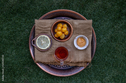 Tea and Lemon Served with Thongyod (Thai Desserts) in Round tray on Green lawn in the park. photo