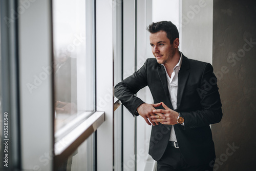 Foto Successful and respectable man looks out the window in the office and leaned on