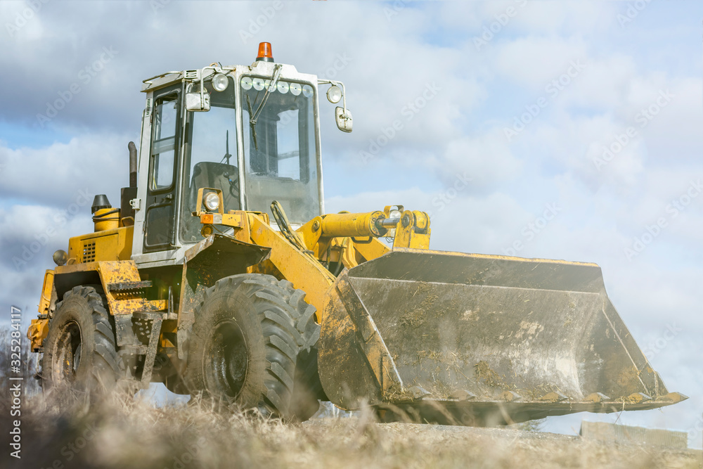 Obraz premium Daylight Yellow loader with a bucket. There is a tint. Close-up