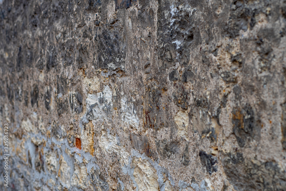 Naklejka premium Old medieval wall made of mortar-fastened stones with traces of repair. Photo at an angle to the wall.