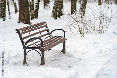 Wooden park bench covered with snow