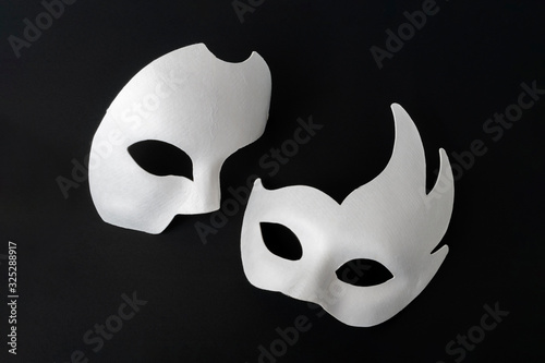 Two white masquerade masks on a black background.