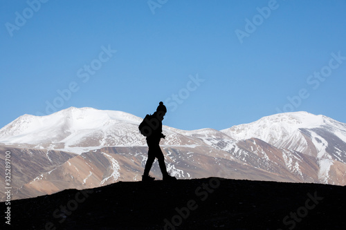 Silhouette of woman hiker stands on the rock in the beautiful mountains view of snowy Tso Moriri Lake in Leh Ladakh india, success concept photo