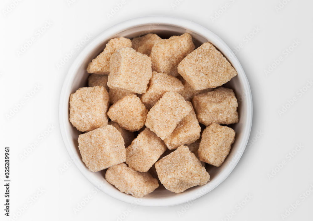 Glass bowl plate of natural brown unrefined sugar cubes on white background. Glass bowl plate of natural brown unrefined sugar cubes on white background.