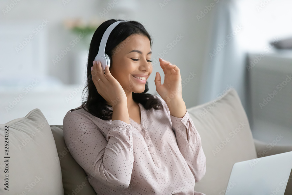 Happy biracial female in headphones using laptop Happy biracial female in headphones using laptop