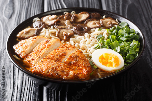 serving of ramen soup with chicken breast, mushrooms, eggs and green onions close-up in a bowl. horizontal