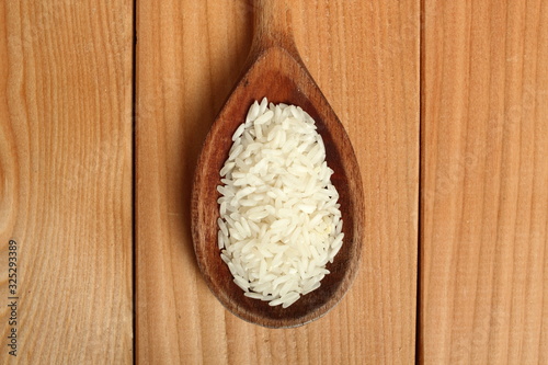 Rice on wooden spoon at plank background. Directly Above.