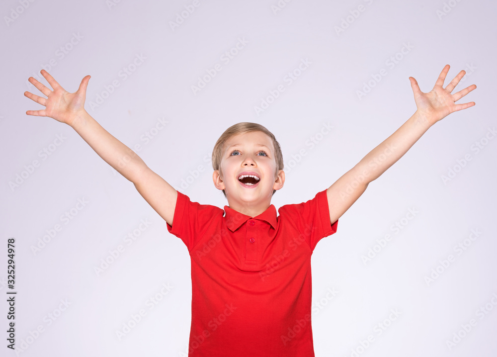 Portrait of a laughing happy boy with raised hands up - isolated on white background. Happy cheerful kid with a hands up. Happy child in a red clothes posing at studio. 8 years old boy looking up Portrait of a laughing happy boy with raised hands up - isolated on white background. Happy cheerful kid with a hands up. Happy child in a red clothes posing at studio. 8 years old boy looking up