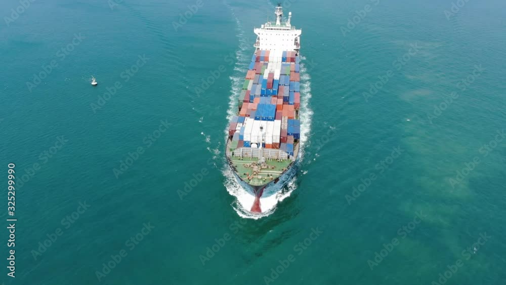Aerial of cargo ship carrying container and running for export goods from cargo yard port to other ocean concept freight shipping ship on blue sky background. Aerial of cargo ship carrying container and running for export goods from cargo yard port to other ocean concept freight shipping ship on blue sky background.