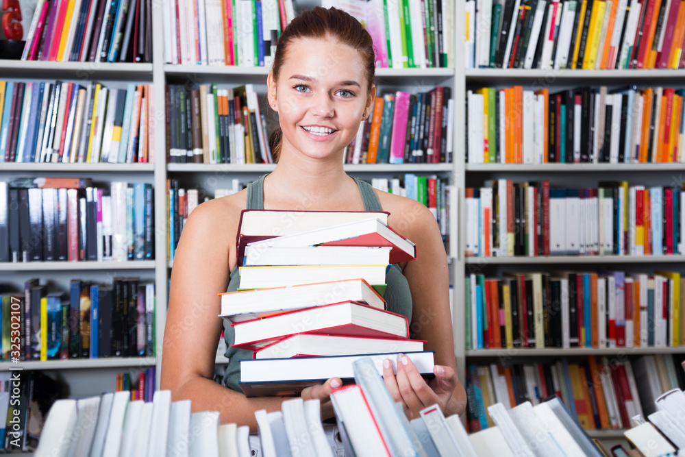 brunete girl chose a lot of books in university library brunete girl chose a lot of books in university library