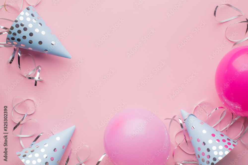 Blue hats, pink balls and silver serpentine on a pink paper background. Holiday background. Copy space