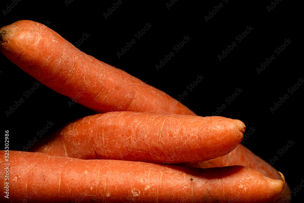Three unpeeled carrot on a black background Three unpeeled carrot on a black background