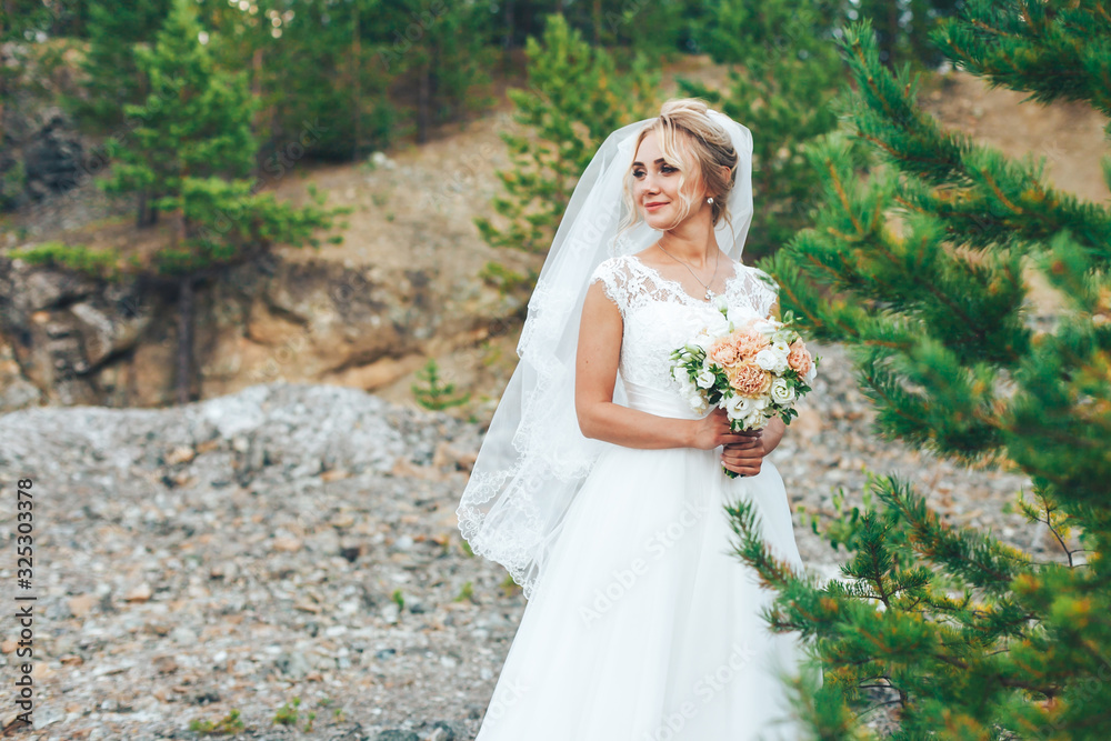 Portrait of the bride against the mountains. The bride stands in the nature of a mountain forest