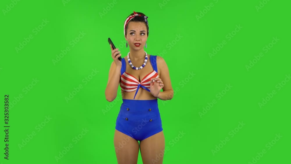 Beautiful girl in a swimsuit is talking for mobile phone and rejoicing . Green screen Beautiful girl in a swimsuit is talking for mobile phone and rejoicing . Green screen