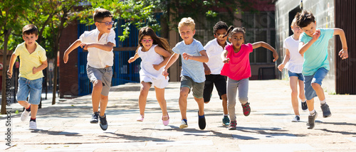 Children running in race and laughing outdoors at sunny day