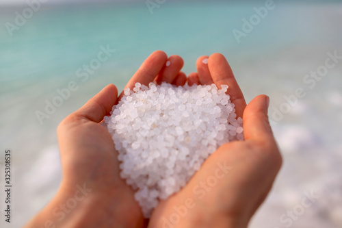 Close-up of the salt from the Death Sea in Jordan in woman<s hands .