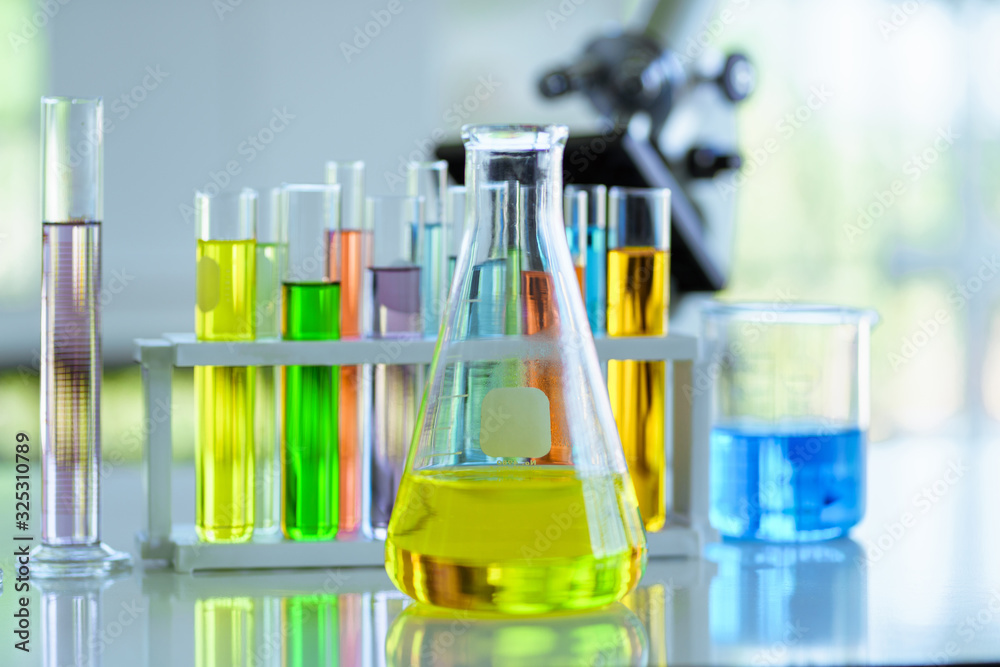 Chemical Flask Glassware with yellow liquids and test tubes on table in Laboratory