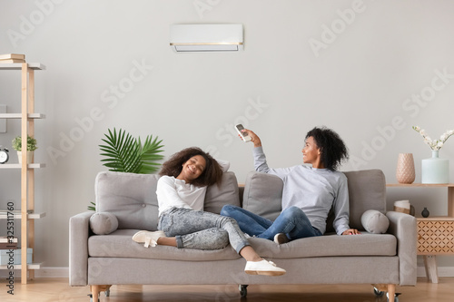 Happy african american family relaxing on sofa under air conditioner