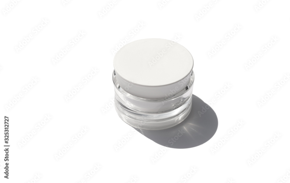 Cosmetic cream in a jar with sunlight on white background