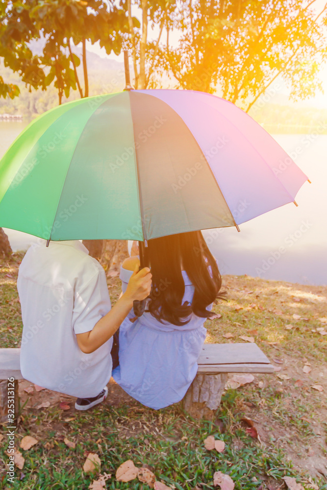 Lesbian Lovers Sitting Together Under The Umbrella Rainbow Colors To