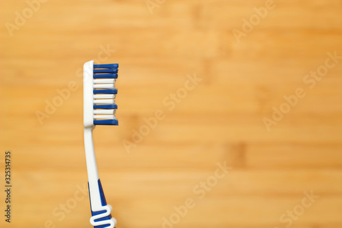 Nahaufnahme einer Zahnbürste mit blauen Borsten vor hellem Holz Hintergrund