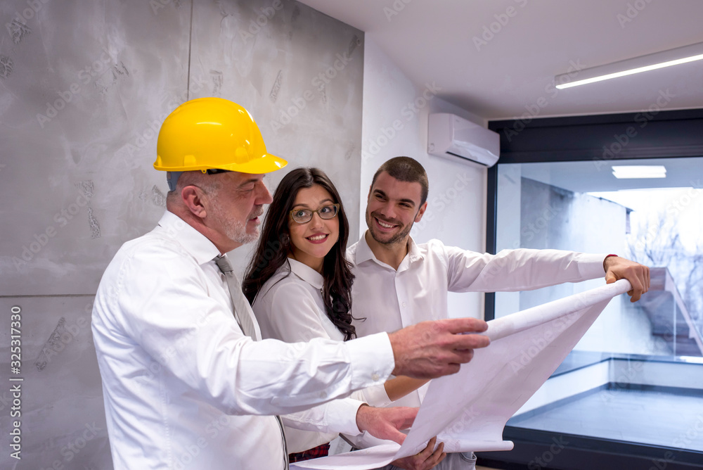 Senior contractor showing plan of new apartment to young couple Senior contractor showing plan of new apartment to young couple