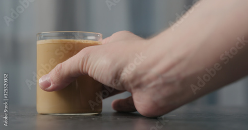 man hand take coffee with cream in glass on concrete countertop