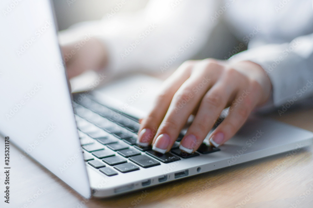Woman working at modern computer. Person buying online at internet. Laptop focused on keyboard detail with blur hand. Woman working at modern computer. Person buying online at internet. Laptop focused on keyboard detail with blur hand.