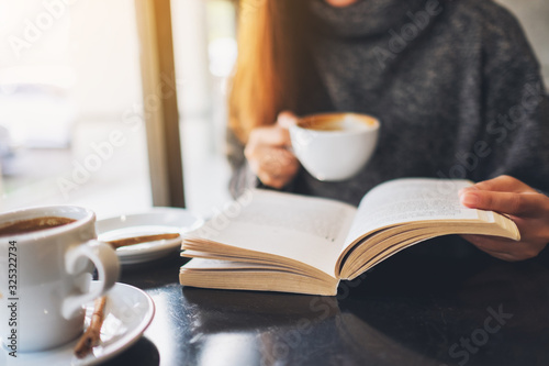 Closeup image of a woman reading a book while drinking coffee in cafe