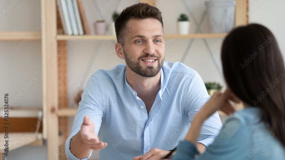 Young man involved in conversation with colleague in office Young man involved in conversation with colleague in office