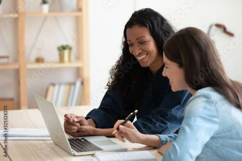 Smiling mixed race employees communicating with clients online in office.