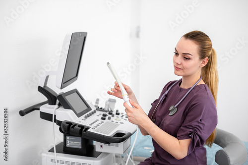 Ultrasound special sensor of modern ultrasonic scanner for intavaginal checkup and small medical condom for it in young woman doctor's hands preparing for a device scan. Helthcare concept photo