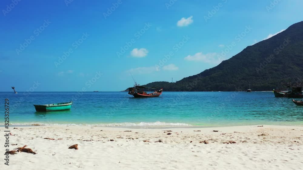 small fishing boats floating in the crystal clear tropical sea. Sandy coast of Thailand small fishing boats floating in the crystal clear tropical sea. Sandy coast of Thailand