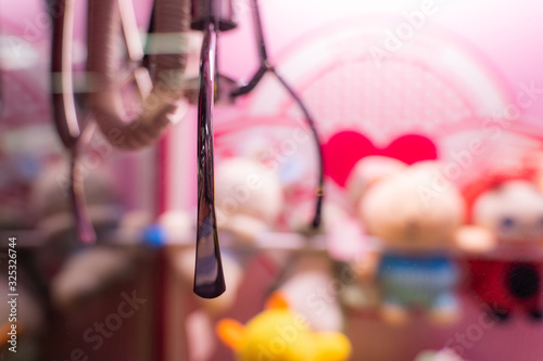 close up claw machine with blurly doll in background  photo