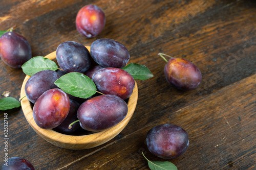 Ripe plums in a wooden bowl. Fresh fruits.
