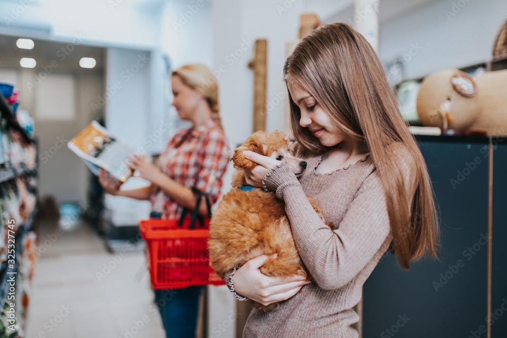 Mother and daughter with their poodle puppy in pet shop. Mother and daughter with their poodle puppy in pet shop.