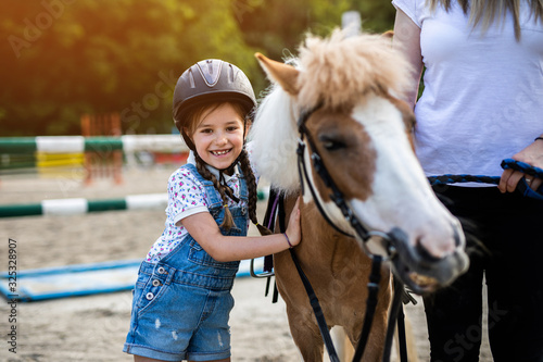Cute little girl and her older sister enjoying with pony horse outdoors at ranch.. © hedgehog94