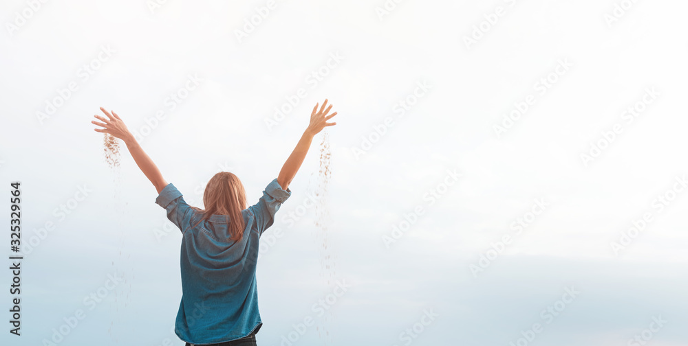 Happy woman in desert with raised hands full of sand, copy space.