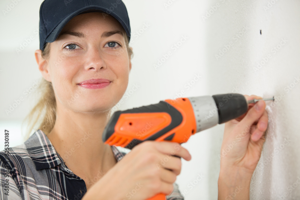female carpenter using a drill on a wood