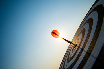 Close up shot red darts arrows in the target center on dark blue sky background. Business target or goal success and winner concept.