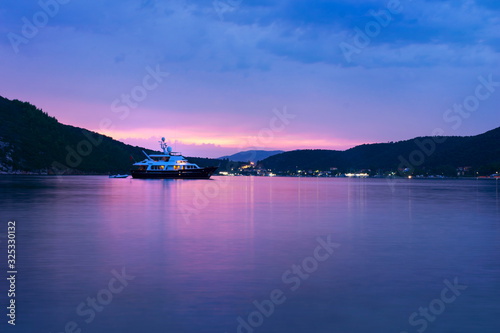 Peaceful seaside bay sunset with luxury boat floating on the calm water and colorful sky