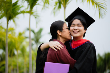 Graduation ceremony. Young female graduate hugging each other with her mother congratulate the student at the university.