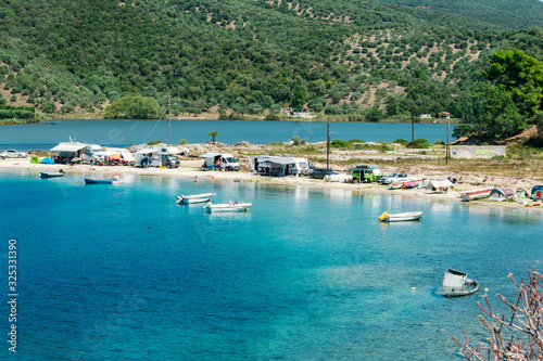 Porto Koufo, Greece, 05/07/2019: View on famous Greek bay with many recreational vehicles parked around the beach and turquoise blue water. Perfect vacation place for camping lifestyle.