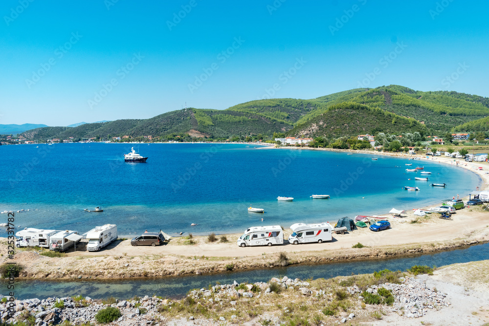 Porto Koufo, Greece, 05/07/2019: View on famous Greek bay with many recreational vehicles parked around the beach and turquoise blue water. Perfect vacation place for camping lifestyle.