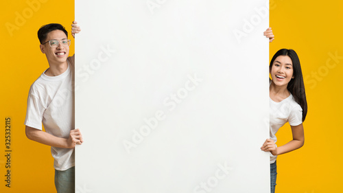 Asian man and woman posing with white empty board