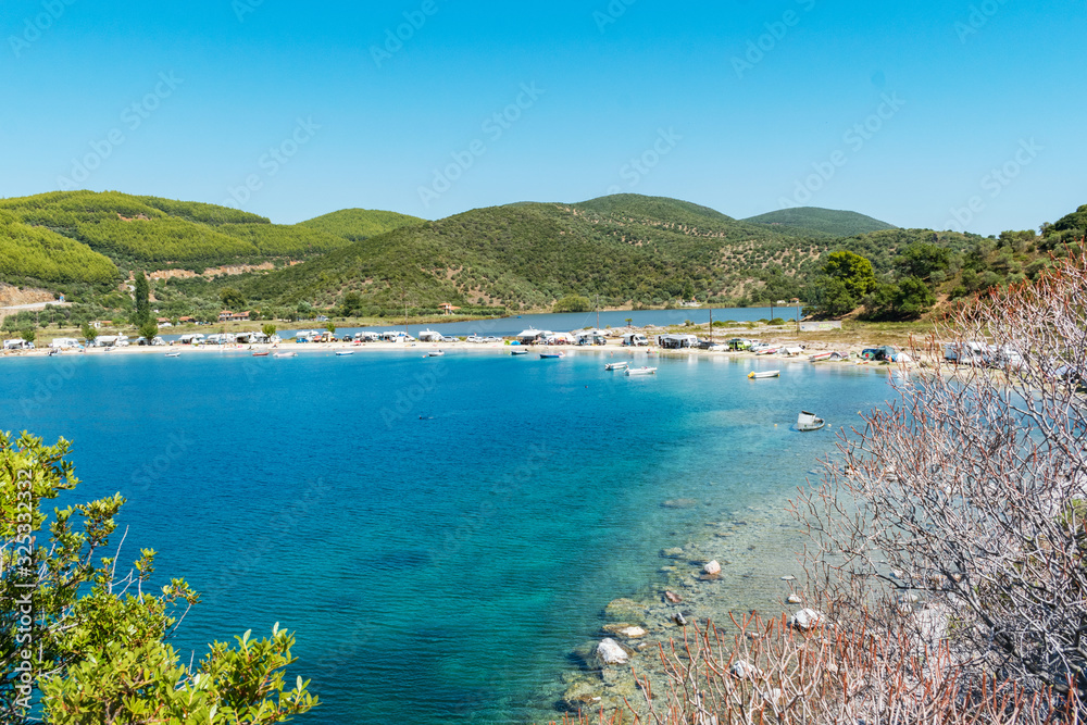 Porto Koufo, Greece, 05/07/2019: View on famous Greek bay with many recreational vehicles parked around the beach and turquoise blue water. Perfect vacation place for camping lifestyle.